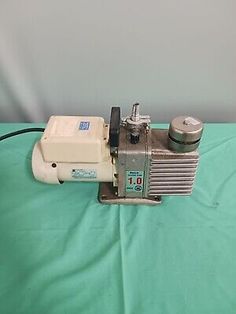 a small machine that is sitting on top of a green sheet with a white background