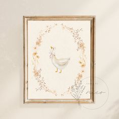 a white duck with a pink ribbon in a frame