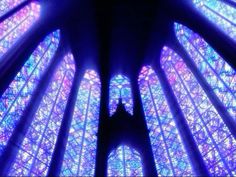 the inside of a large cathedral with multiple colored stained glass designs on it's walls