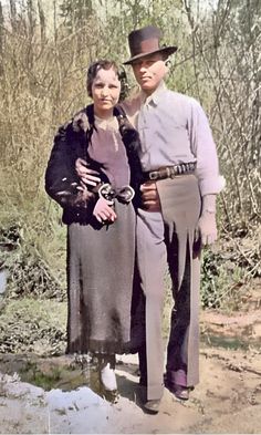 an old photo of two people standing next to each other in front of some trees