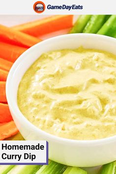 a white bowl filled with dip surrounded by carrots and celery