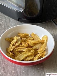 a red and white bowl filled with chips next to an open toaster oven door