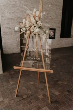 an easel with flowers on it is sitting in the middle of a brick floor