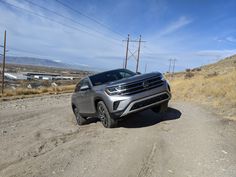 a grey car is driving down a dirt road