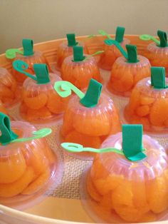 small plastic pumpkins are sitting on a tray with green paper clips stuck to them