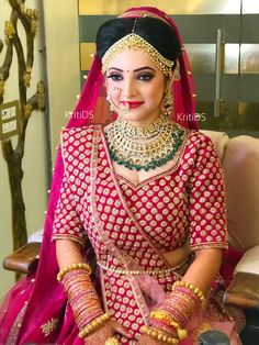 a woman in a red and gold bridal outfit sitting on a chair with jewelry