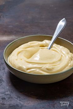 a bowl filled with cream sitting on top of a wooden table next to a spoon