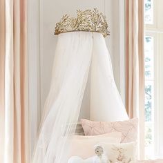 a bed with a white canopy and a gold crown on it's headboard