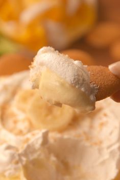 a close up of a person holding a piece of bread with whipped cream on it