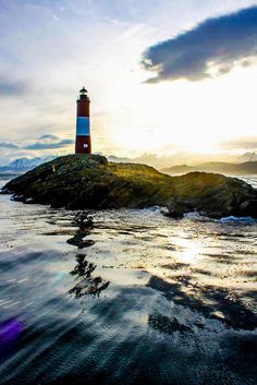 a light house sitting on top of a small island in the middle of the ocean