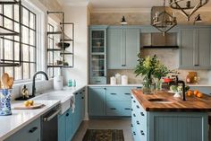 a kitchen filled with lots of blue cabinets and counter top space next to a window