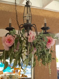 a chandelier with pink flowers hanging from it's sides and greenery