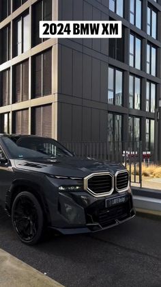 a black bmw suv parked in front of a tall building with the words bmw on it