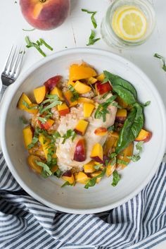 a white bowl filled with food next to a glass of orange juice and a fork