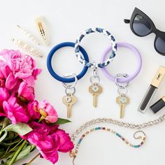 various items are laid out on a white surface including sunglasses, bracelets and flowers