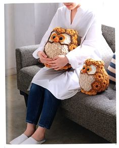 a woman sitting on a couch holding an owl pillow