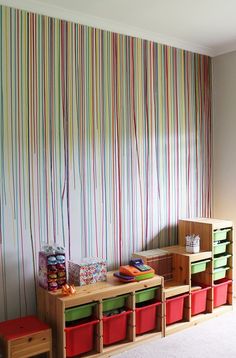 a child's room with colorful striped wallpaper and storage bins on the floor