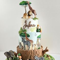 a three tiered cake with zebras, giraffes and elephants on it