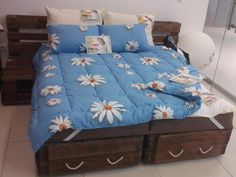 a bed with blue sheets and white daisies on it, sitting in a room