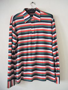 Vintage longsleeve polo shirt from the 1990s. Beautiful stripe pattern in vibrant colour mix. Big collar. Halfway buttoned front. Decorative tuck on the back. Buttoned cuffs. Style with your favorite jeans and sunglasses for a preppy look! BRAND: einhorn ERA: 1990s COLOR: Blue, white, red, green stripes MATERIAL: 65% polyester, 35% cotton SIZE: M (please check measurements) MEASUREMENTS: Pit to pit 52cm, length without collar 65cm, sleeve length from shoulder 60cm CONDITION: Very good vintage co Classic Long Sleeve Polo Shirt With Contrast Stripes, Striped Long Sleeve Polo Shirt, Cotton Long Sleeve Polo Shirt With Contrast Stripes, Casual Long Sleeve Polo Sweater With Striped Collar, Casual Long-sleeve Polo Sweater With Striped Collar, Retro Long Sleeve Cotton Polo Sweater, Collared Tops With Vertical Stripes For Fall, Multicolor Long Sleeve Top With Vertical Stripes, Retro Striped Polo Shirt With Polo Collar