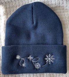 a blue beanie hat with white flowers on it sitting on top of a bed