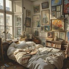 an unmade bed in a bedroom with lots of pictures on the wall