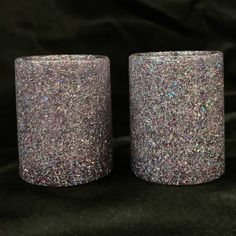 two glitter candles sitting side by side on a black background