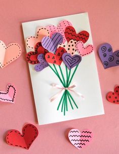 valentine's day card with paper hearts and flowers on it, surrounded by cut out hearts