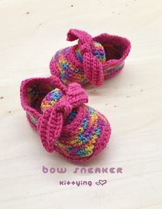 two crocheted baby shoes sitting on top of a wooden table