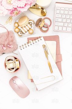 an office desk with pink flowers, notebook and computer mouse on it's side