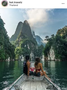 two people are sitting on the back of a boat looking out at mountains and water