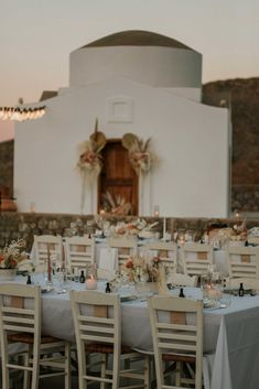 an outdoor dining area with tables and chairs set up for a formal dinner in front of a church