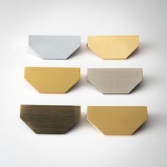 four different colors of metal on a white surface with one yellow and the other silver