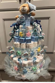 a diaper cake made to look like a baby's first birthday cake with a teddy bear on top