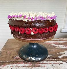 a chocolate cake with raspberries and flowers on top