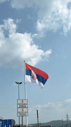 a flag flying in the wind next to a street sign