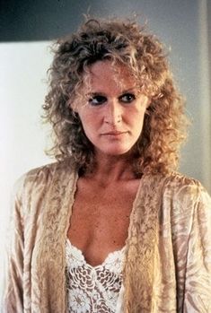 an older woman with curly hair wearing a cardigan and lace top looking at the camera