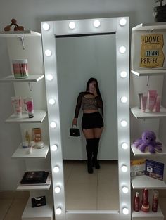 a woman taking a selfie in front of a mirror with light bulbs on it