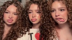 three women with curly hair are making funny faces