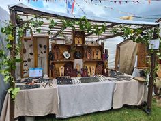 an outdoor market with lots of items on the table and in front of it is a tent