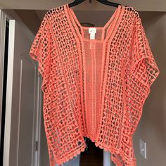 an orange crocheted top hanging on a hanger