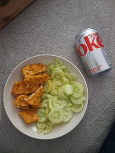 a white plate topped with cut up cucumbers next to a can of coke