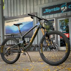 a mountain bike is parked in front of a building with yellow leaves on the ground