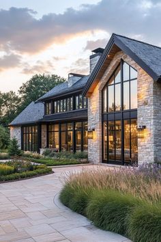 a large house with lots of windows and plants in front of the building at sunset