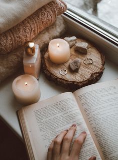 an open book sitting on top of a wooden table next to candles and other items