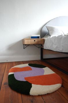 a white bed sitting next to a wooden table on top of a hard wood floor