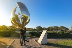 two people standing next to each other near a sculpture