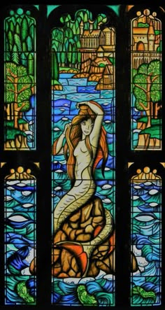 a stained glass window with a mermaid on it's body and water in the background