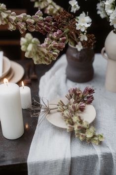 the table is set with white candles and flowers