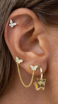 a woman wearing gold ear piercings with butterflies on the back of her ear and chain behind her ear